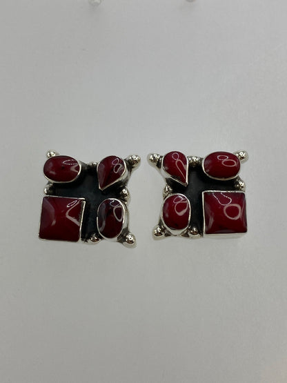 Par de aretes de plata con coral rojo engastado, sobre fondo blanco