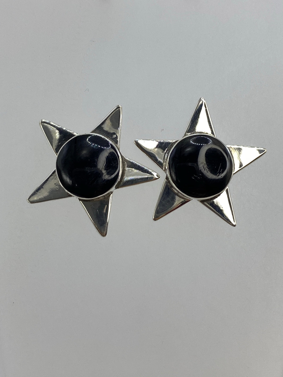 Par de aretes en forma de estrella de plata 925 con ónix negro engastada en el centro