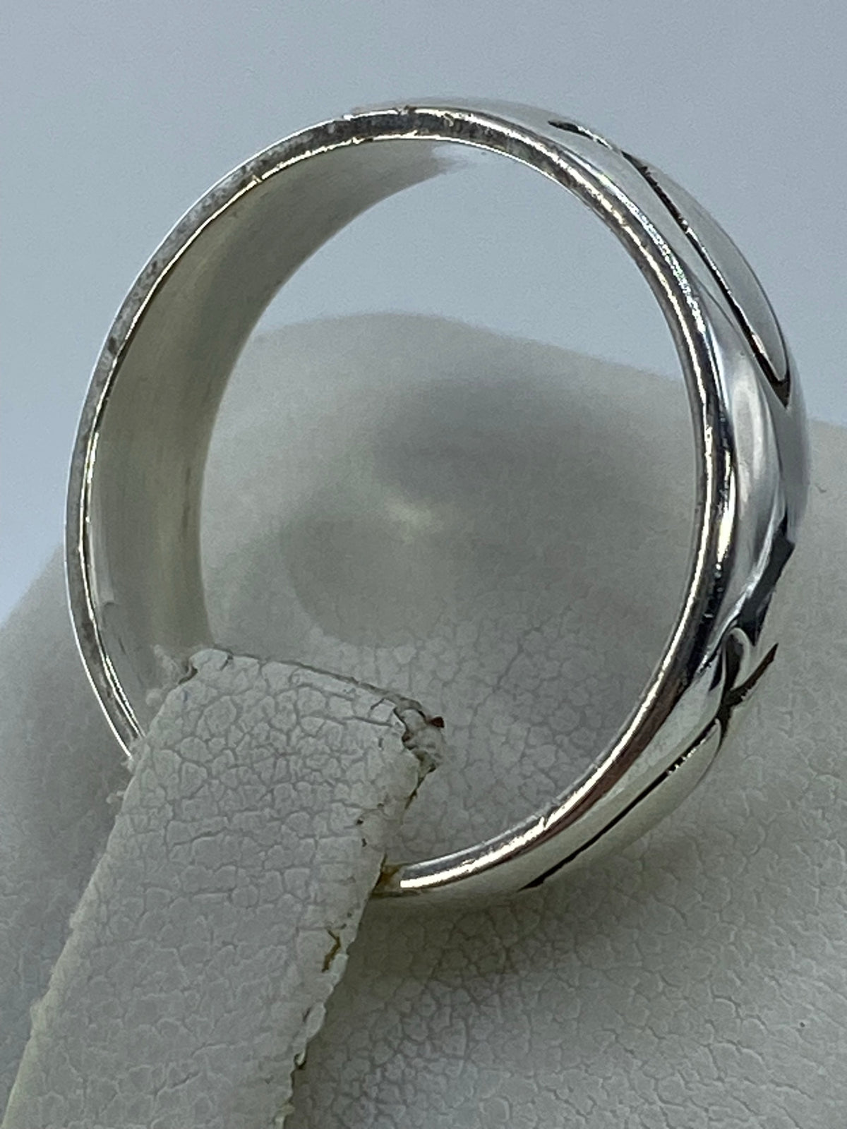 Anillo de plata sin piedras puesto en el dedo, banda ancha y pulida