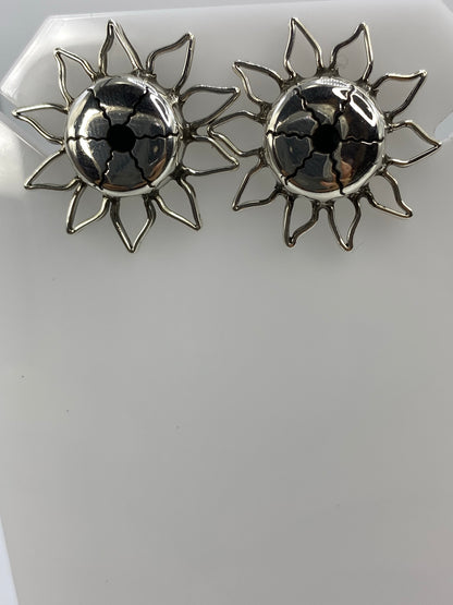 Aretes de plata calado girasol sobre fondo blanco mostrando detalle de precisión