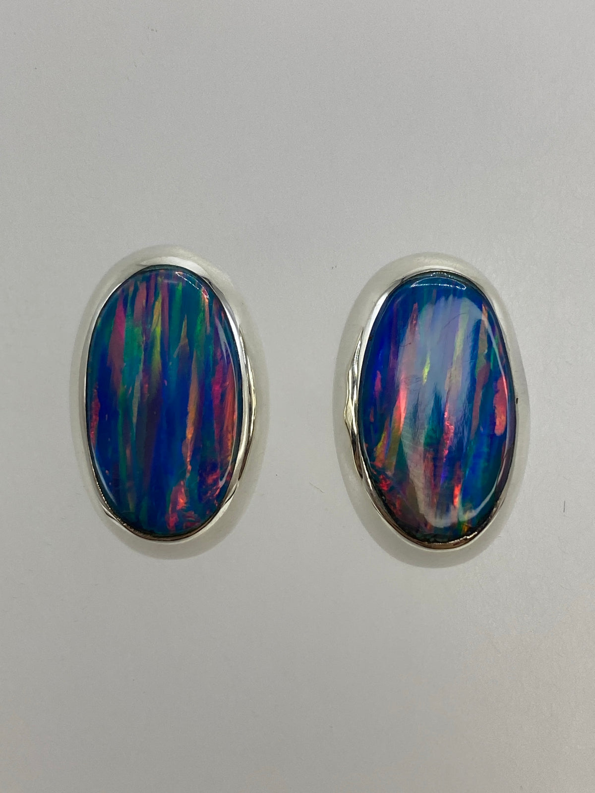 Par de aretes de plata con ópalo de fuego multicolor sobre fondo blanco