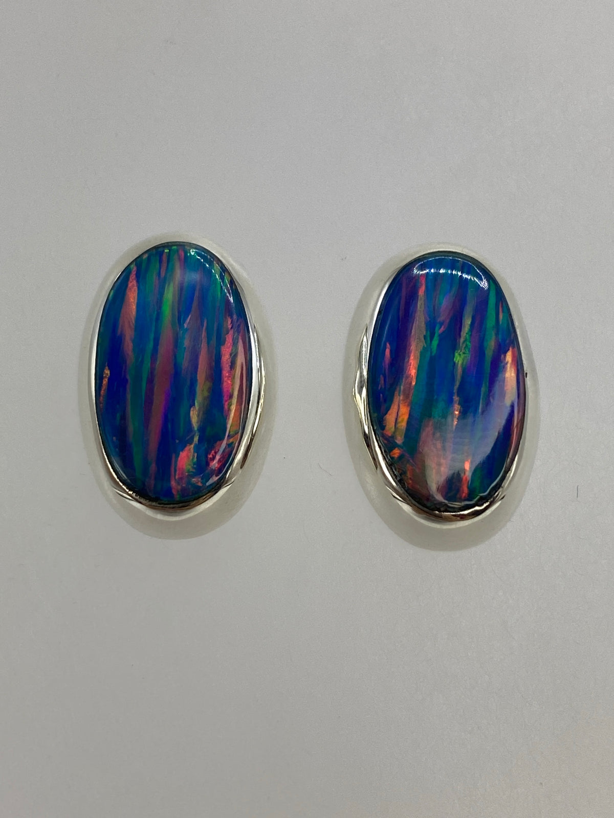 Detalle frontal de un arete mostrando los colores azul, rojo y verde del ópalo