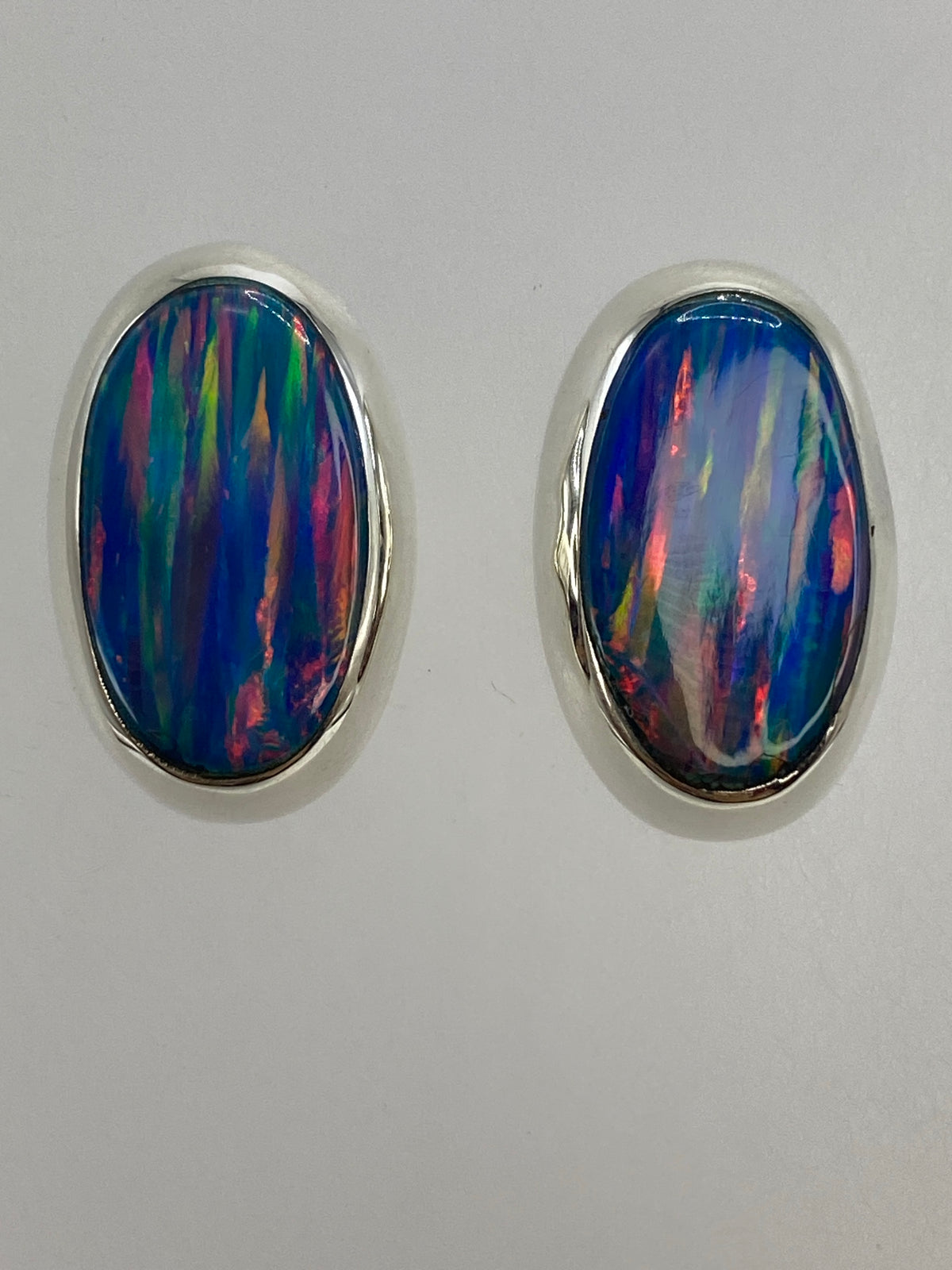 Aretes de ópalo de lado, mostrando el engaste de plata y la profundidad de la piedra