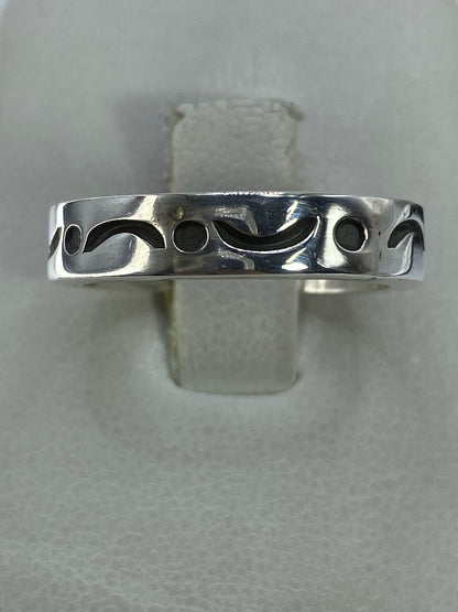 Anillo de plata 925 minimalista con detalle de curvas y círculos, visto desde arriba sobre fondo gris