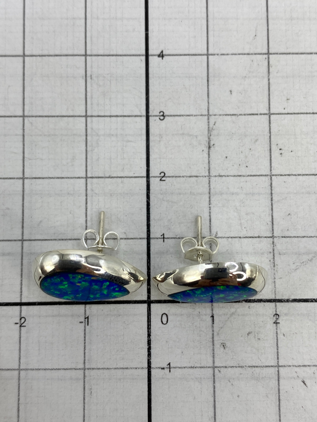 Aretes sobre fondo blanco mostrando la iridiscencia azul del ópalo