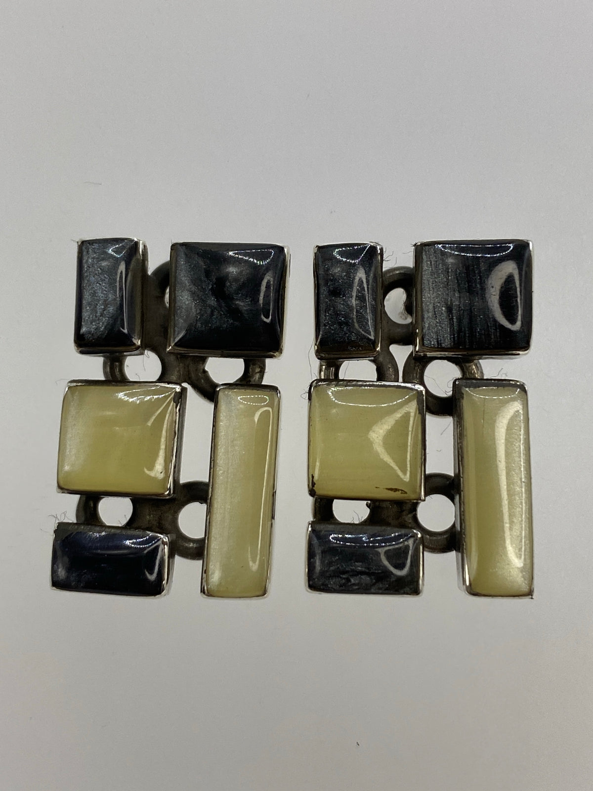 Aretes de plata con coral blanco e incrustación de lapislázuli negro, vistos de frente