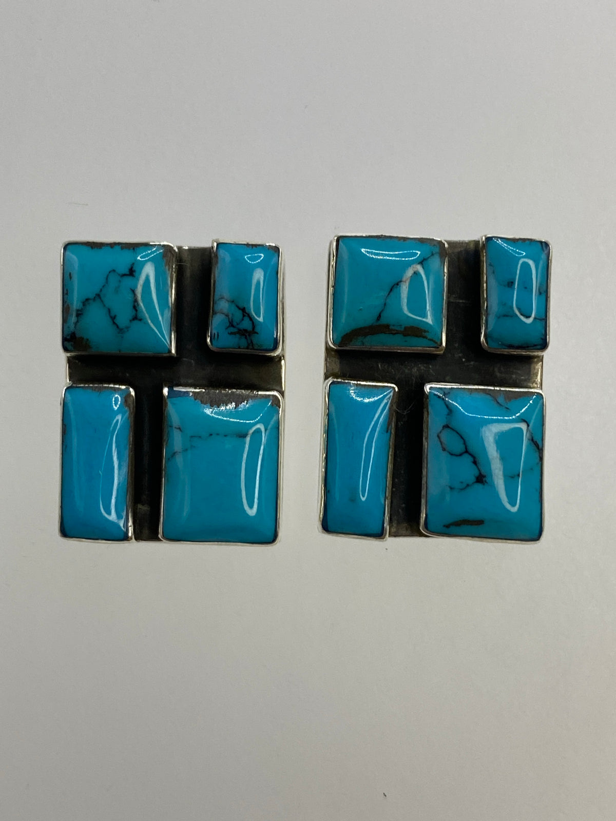 Par de aretes de plata 925 con turquesa azul engastada, vista frontal sobre fondo blanco