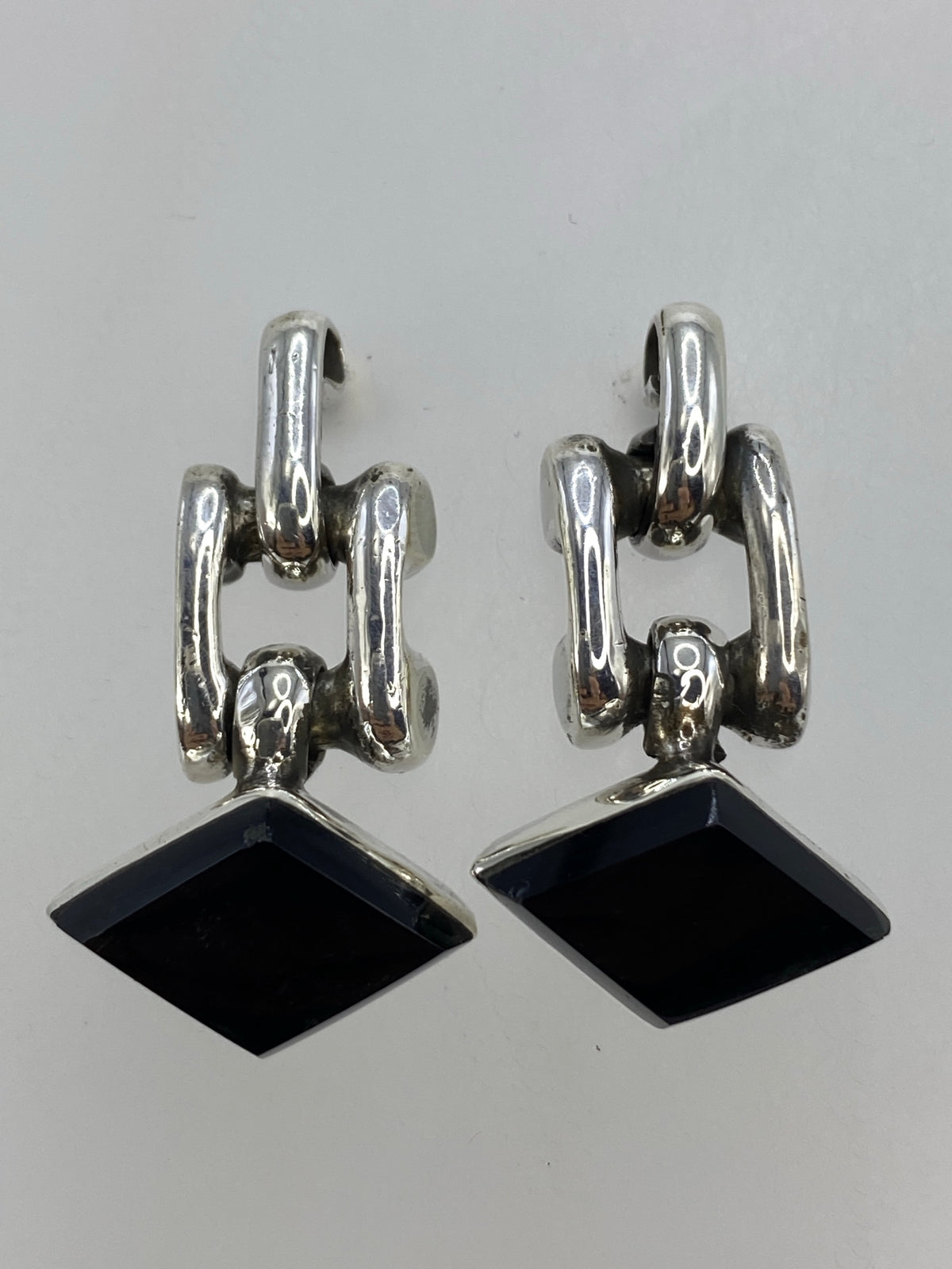 Par de aretes de plata con ónix negro en forma de gota elongada, vista frontal