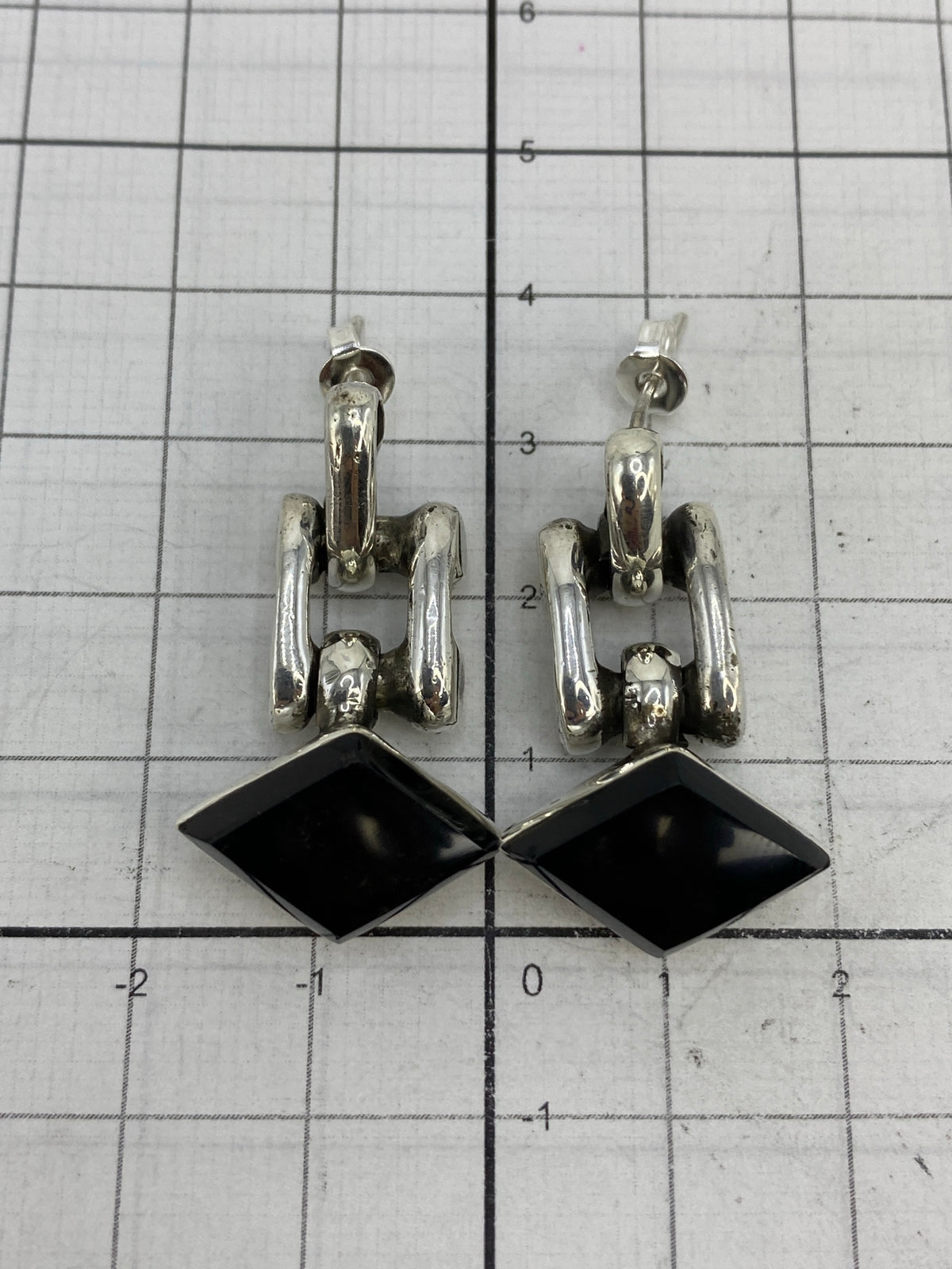 Escala comparativa de los aretes de 3.4 cm sobre cuadrícula milimetrada