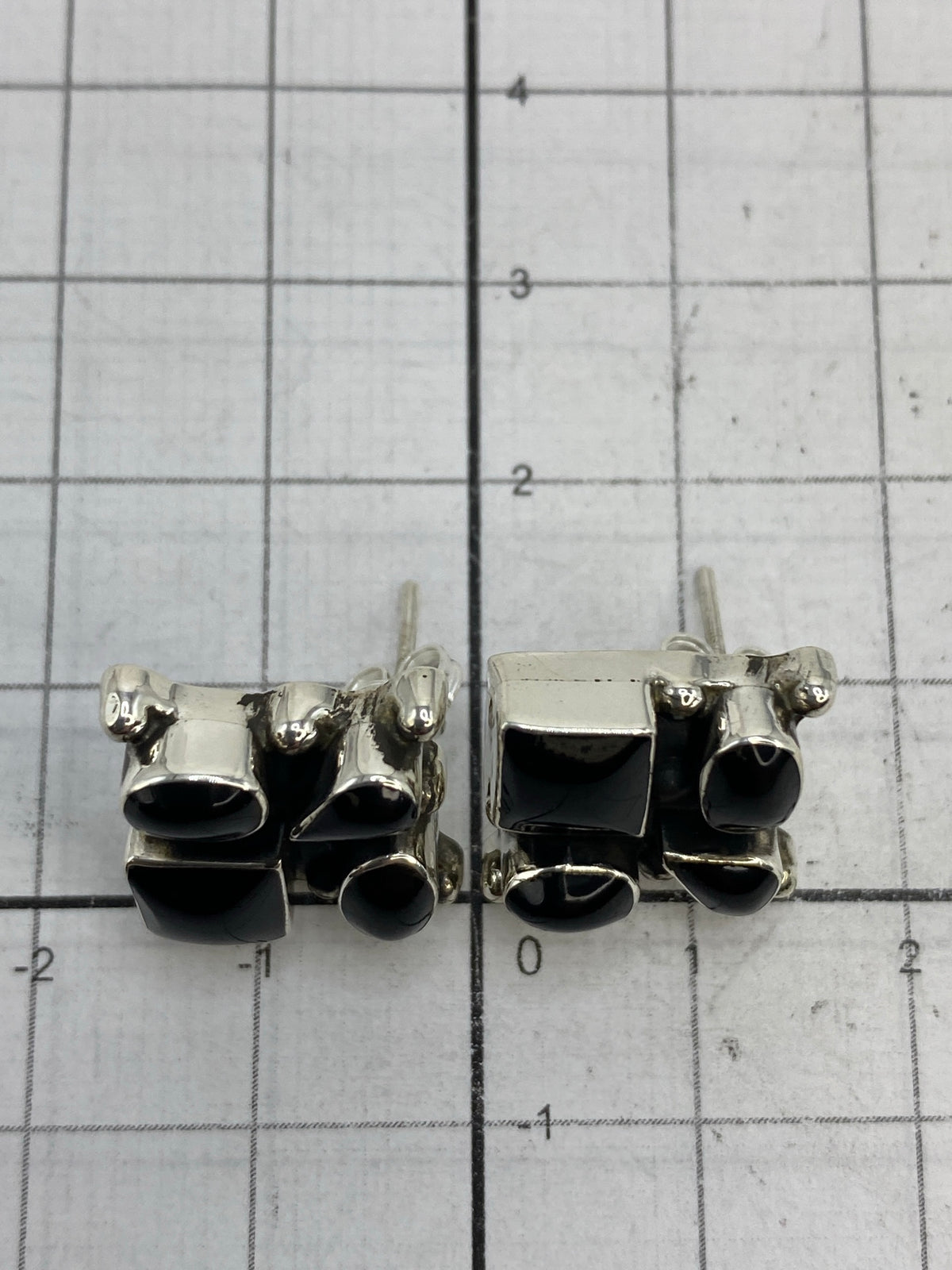 Escala de medida: aretes de 1.5 × 1.4 cm comparados con rejilla