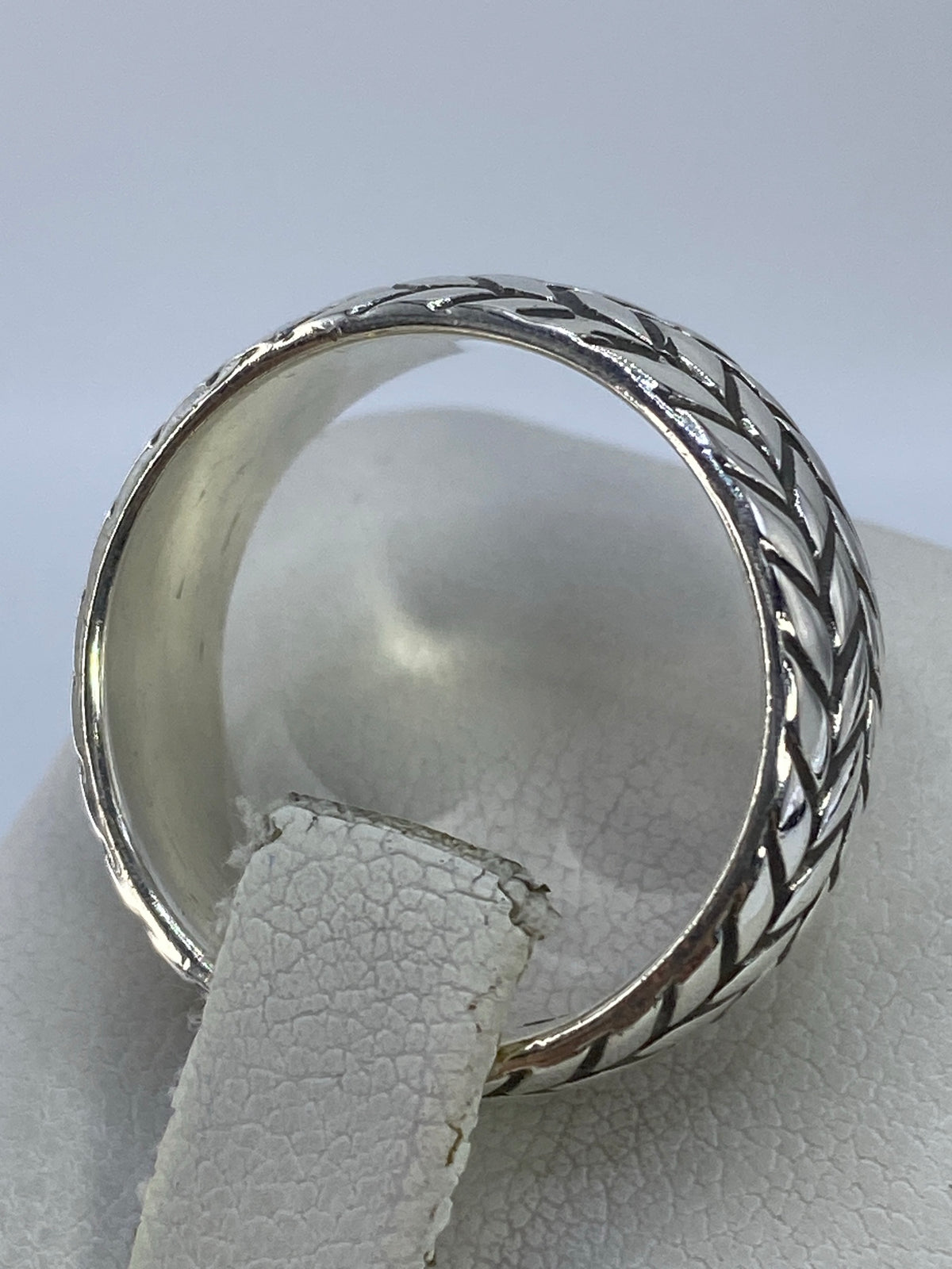 Anillo puesto en dedo corazón de mujer, destacando el diseño trenzado