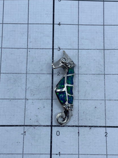 Dije sobre escala con medida de 2.9 cm de largo, tamaño de moneda