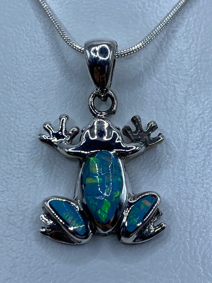 Detalle del dije rana mostrando la incrustación de ópalo de fuego con tonos azules