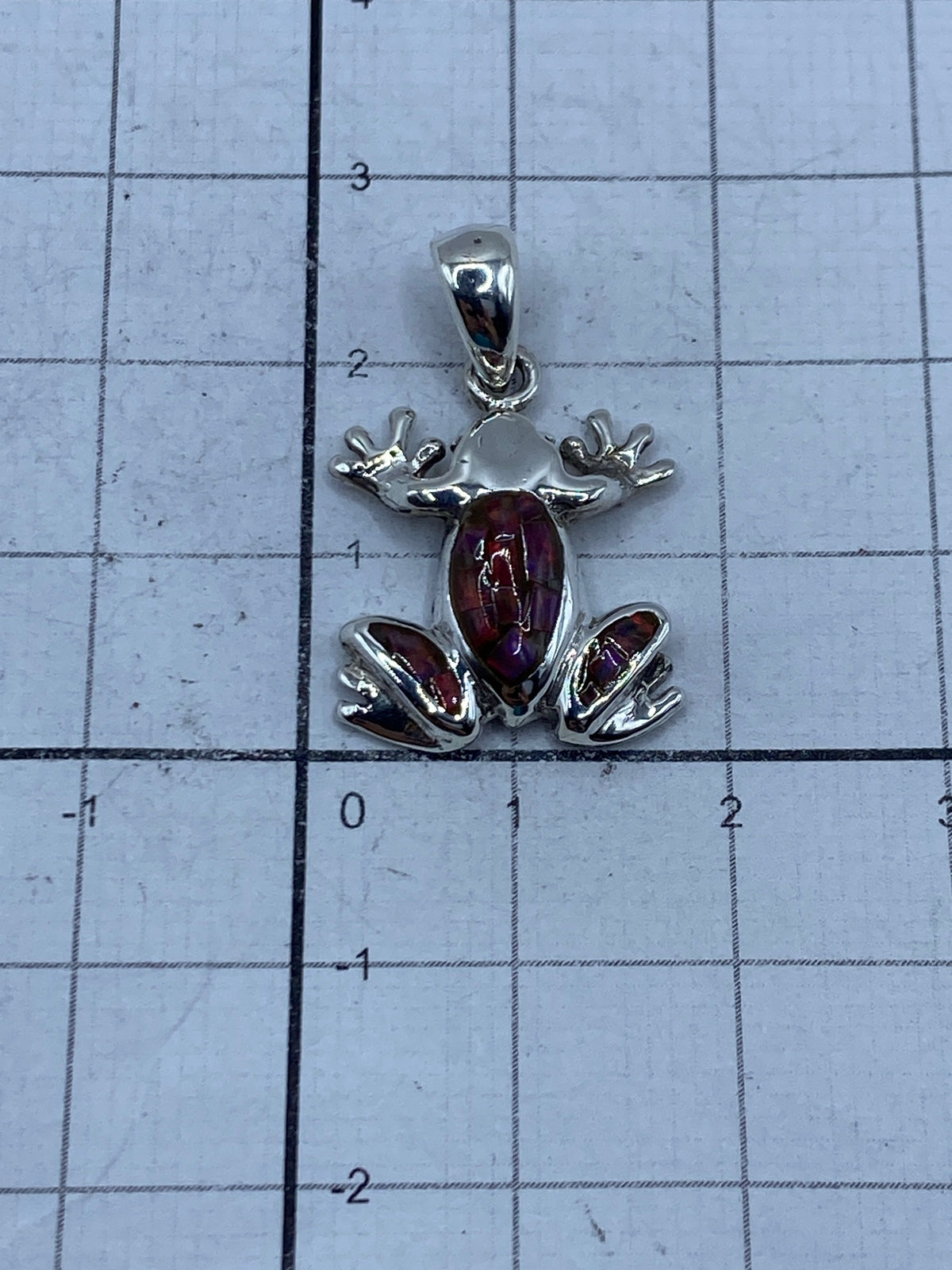 Rana de plata sobre regla — mide 2.7 cm de largo, tamaño de moneda