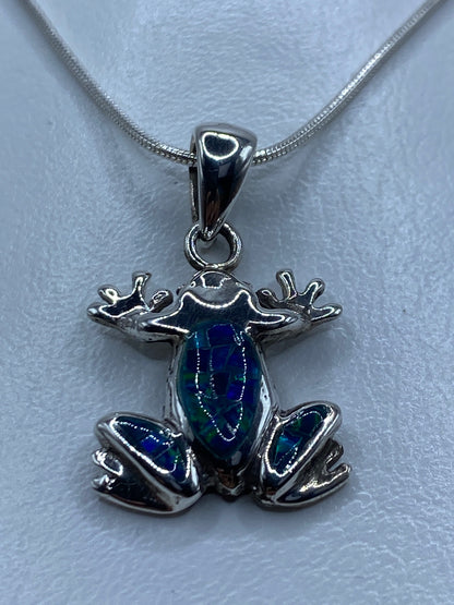 Detalle del ópalo de fuego azul incrustado en el cuerpo de la rana de plata