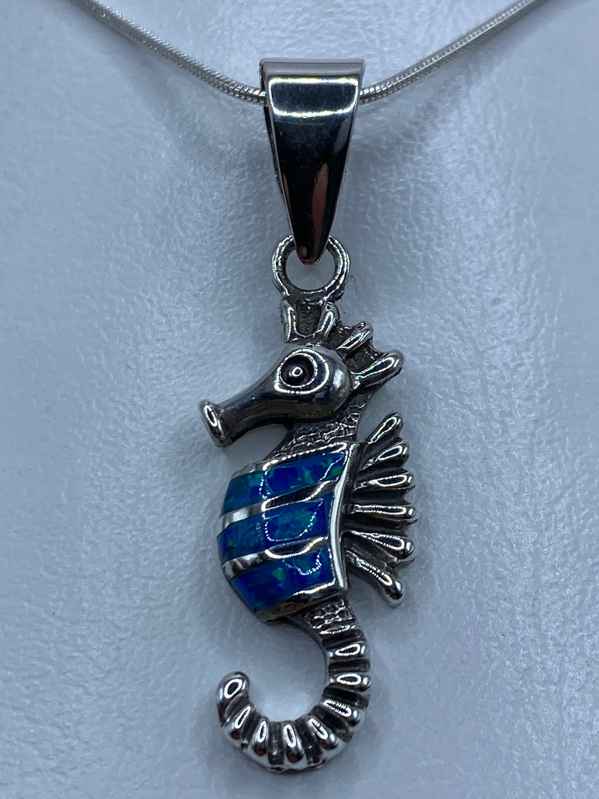 Dije caballito de mar en plata 950 con ópalo azul engastado, colgando en cadena de plata