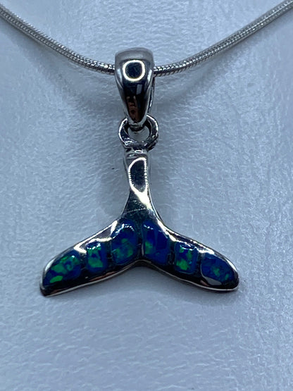 Dije en forma de aleta de plata 950 con ópalo de fuego azul, visto de frente sobre cadena de serpentina