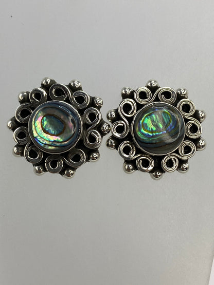 Par de aretes de plata con concha de abulón iridiscente, vistos de frente mostrando el brillo azul y verde