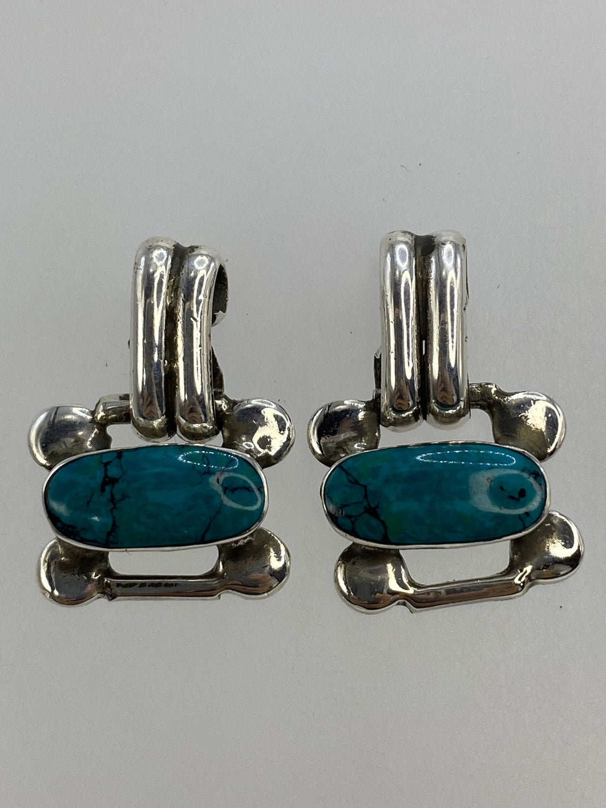 Aretes medidos en regla de centímetros mostrando 2.5 cm de largo