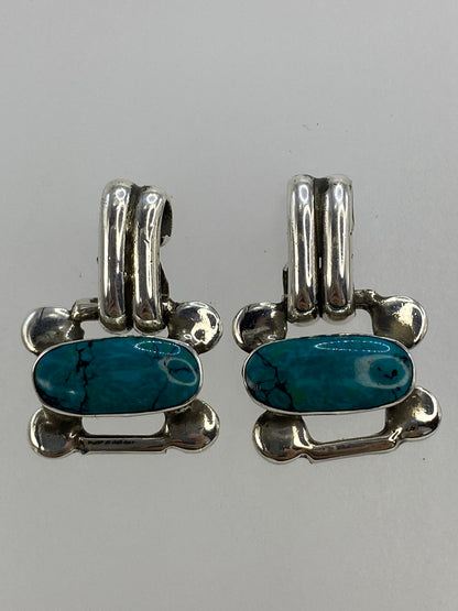Aretes medidos en regla de centímetros mostrando 2.5 cm de largo