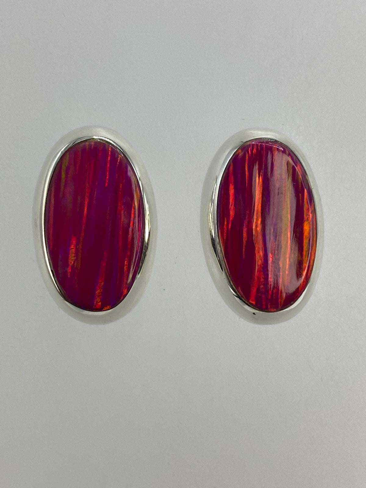 Par de aretes de plata con ópalo de fuego rosa, vista frontal mostrando los reflejos cálidos