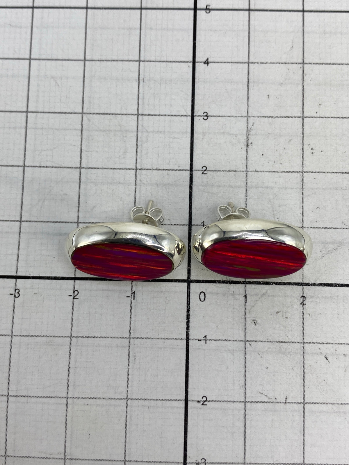Aretes sobre fondo blanco destacando el brillo y color rosa del ópalo