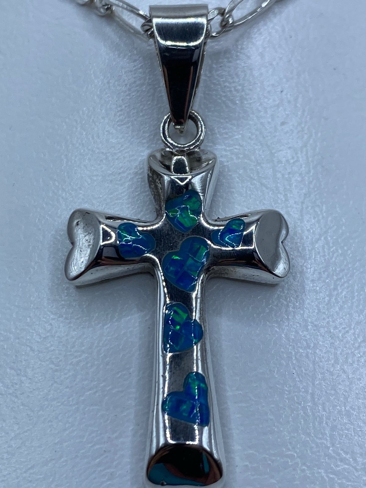 Dije religioso de cruz con piedra azul en escala de centímetros