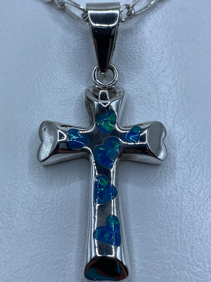 Dije religioso de cruz con piedra azul en escala de centímetros