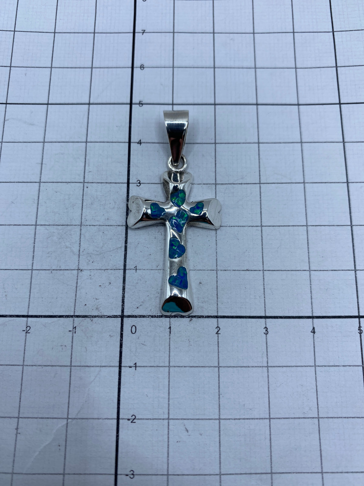 Cruz de plata 950 sobre fondo gris mostrando el Quinto y brillo del ópalo