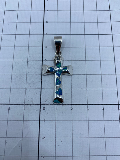 Cruz de plata 950 sobre fondo gris mostrando el Quinto y brillo del ópalo