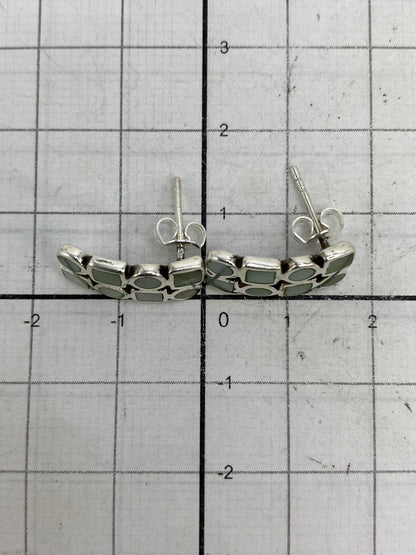Aretes sobre fondo blanco, escala al lado mostrando tamaño real de 1.5 cm