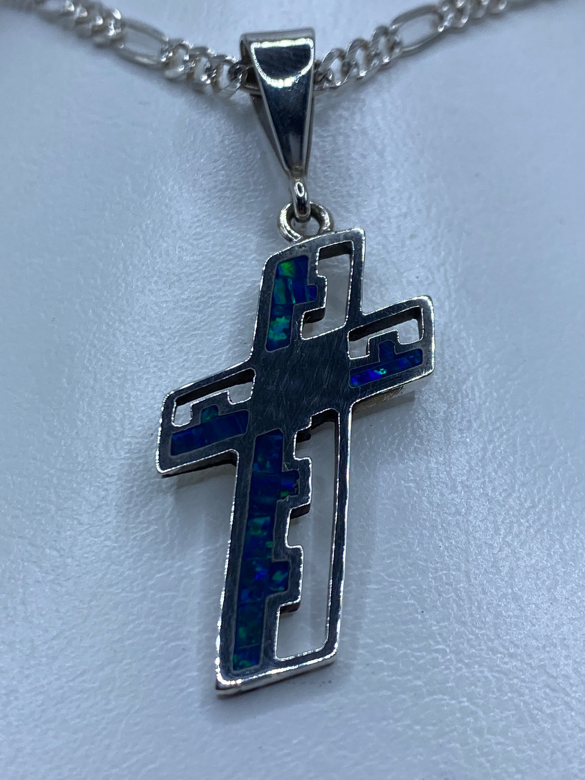 Detalle del ópalo azul incrustado en la cruz de plata, mostrando los tonos índigo y verde