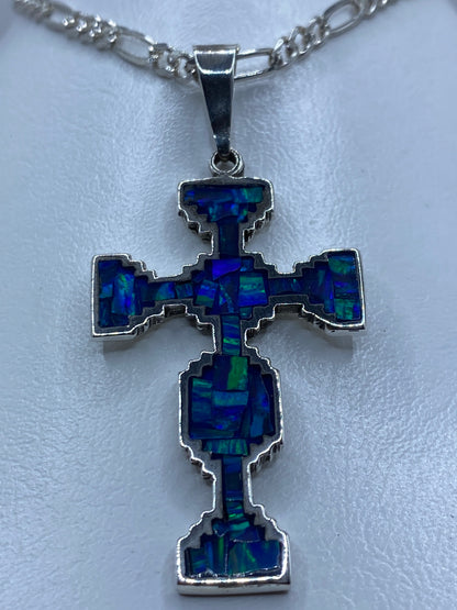 Dije cruciforme de plata 950 con ópalo de fuego azul, vista lateral mostrando el grosor y el engaste artesanal