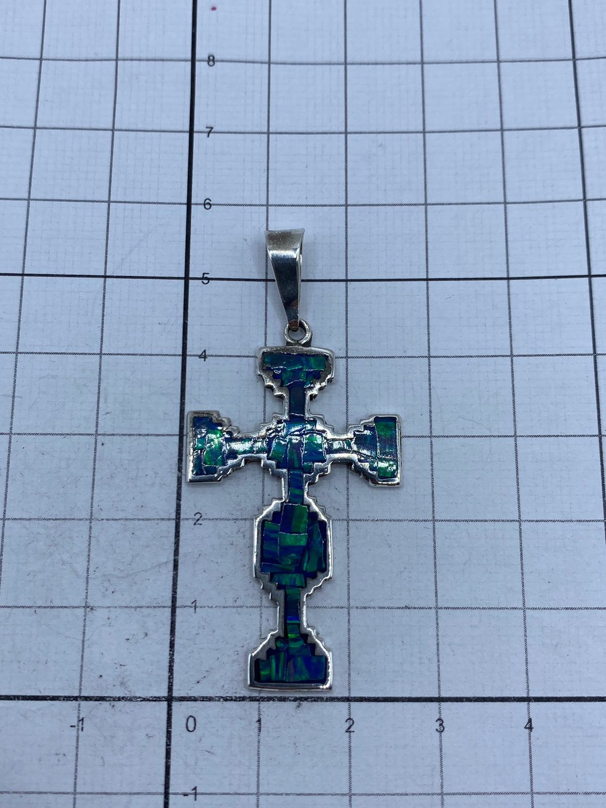 Dije cruz de 5.5 cm sobre escala métrica mostrando tamaño y el Quinto 950 de México