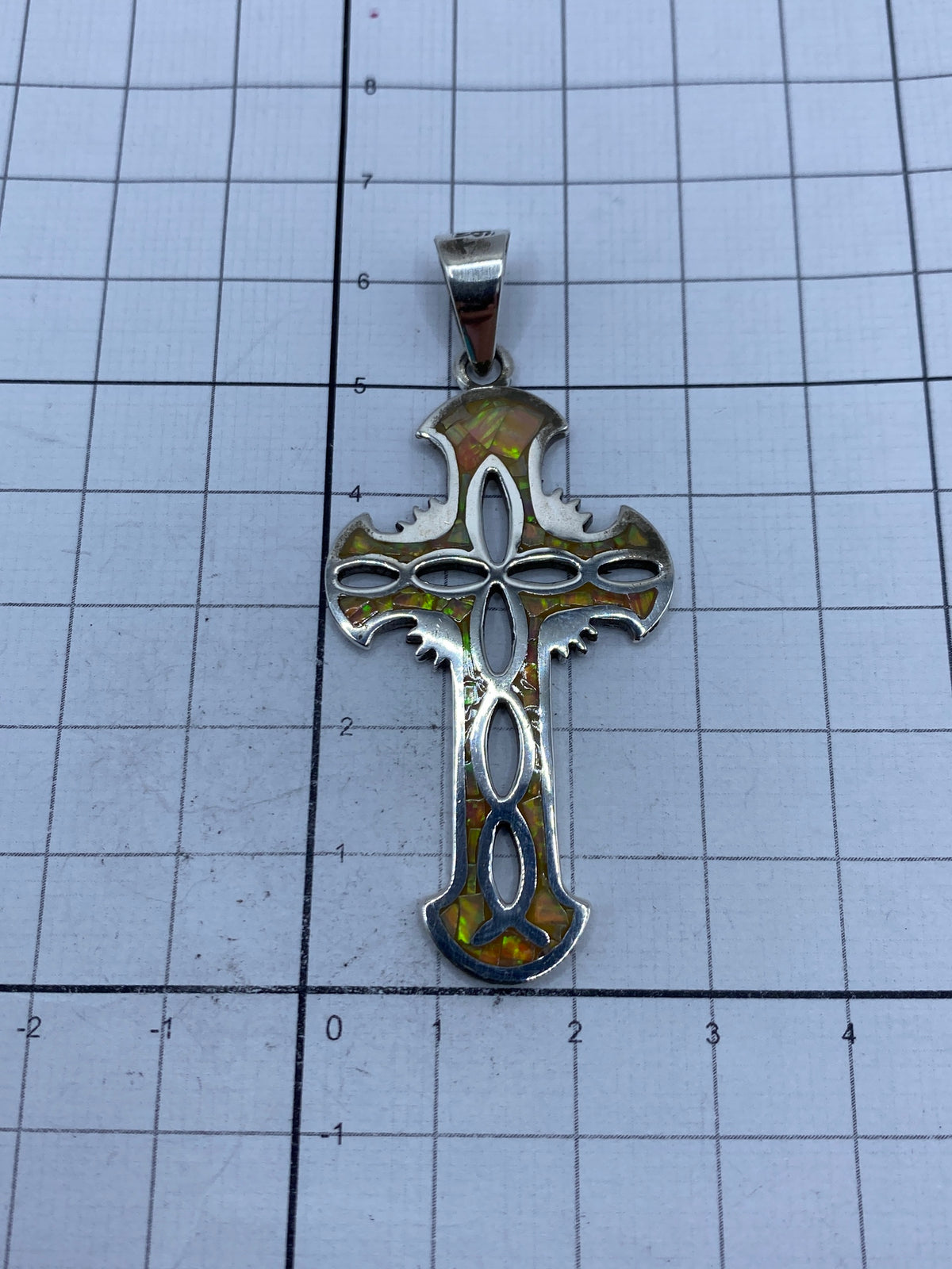 Cruz religiosa con alas de plata 950 sobre escala de medición mostrando 6.3 cm de largo