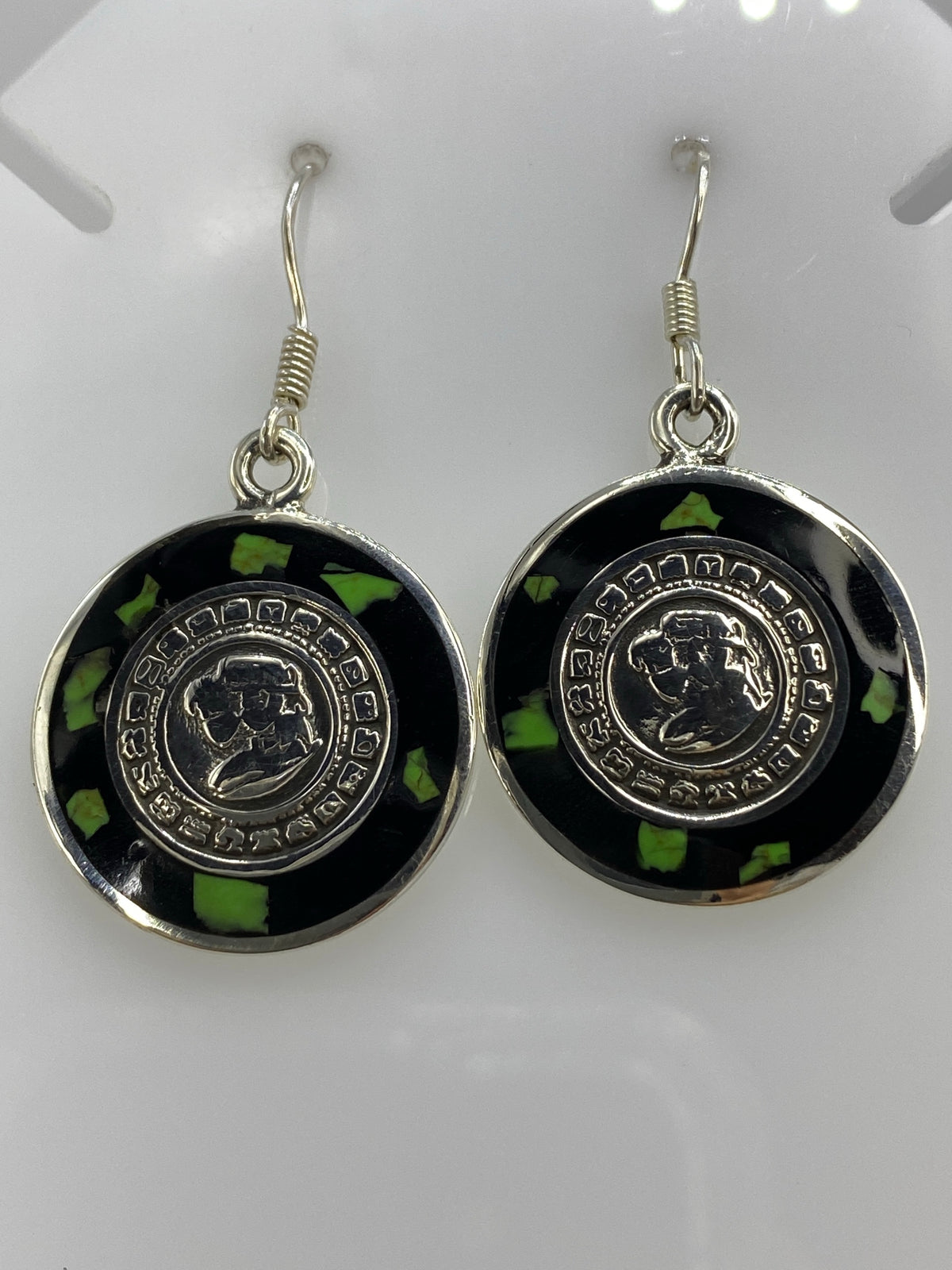 Detalle frontal de los glifos circulares del Calendario Azteca en los aretes de ónix
