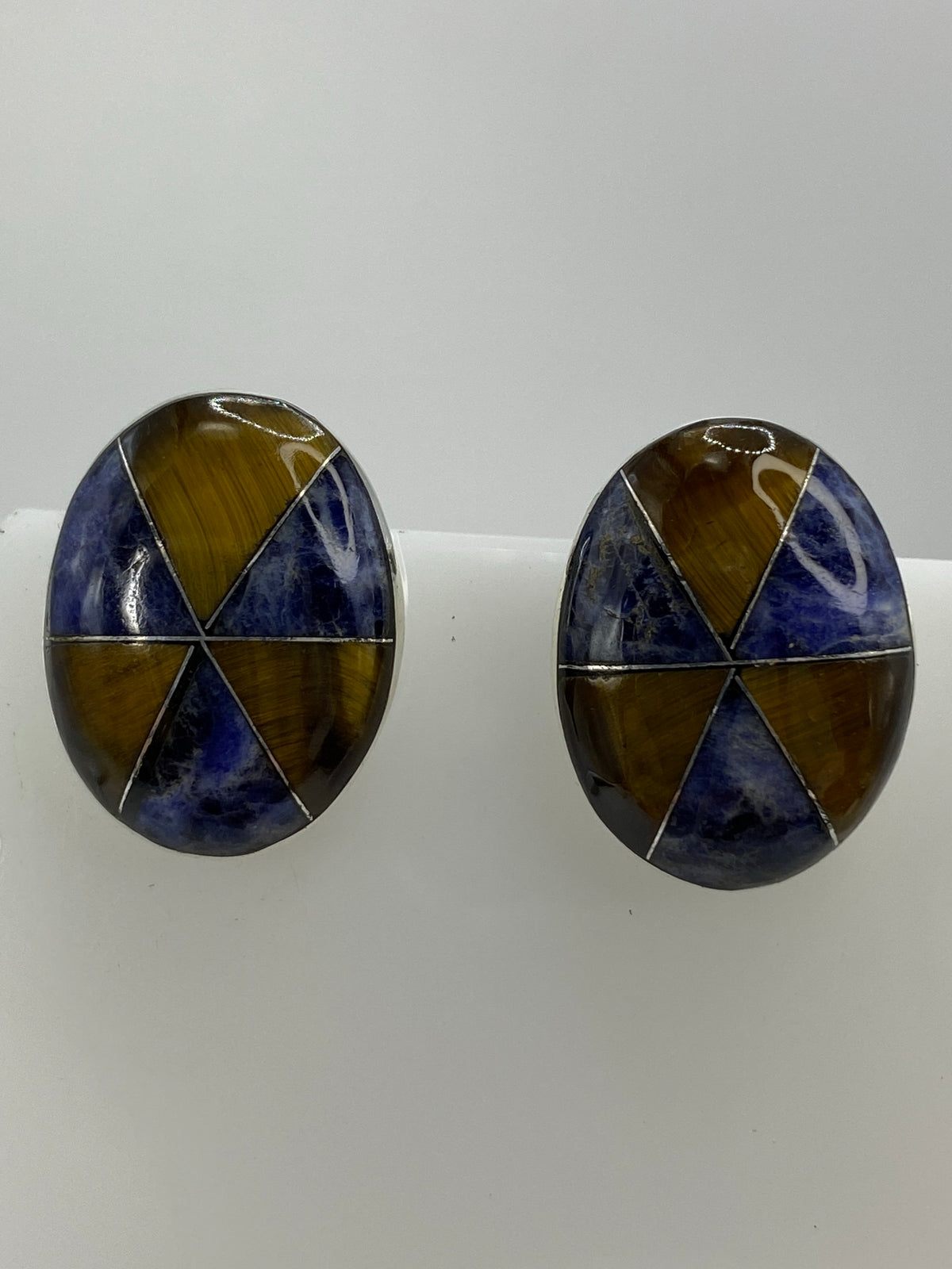 Detalle frontal de los aretes mostrando la combinación de piedras y el acabado pulido de la plata