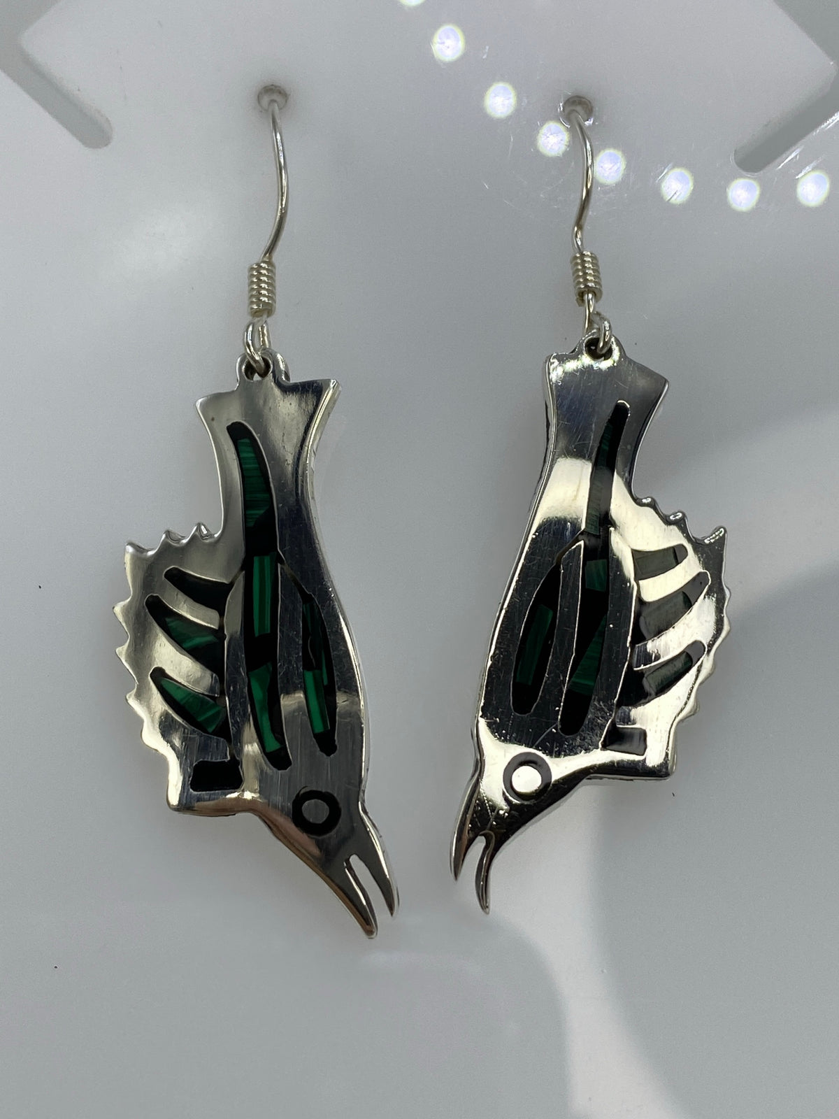 Detalle frontal de los aretes de plata con ópalo de fuego verde brillante y lineas satinadas de las alas