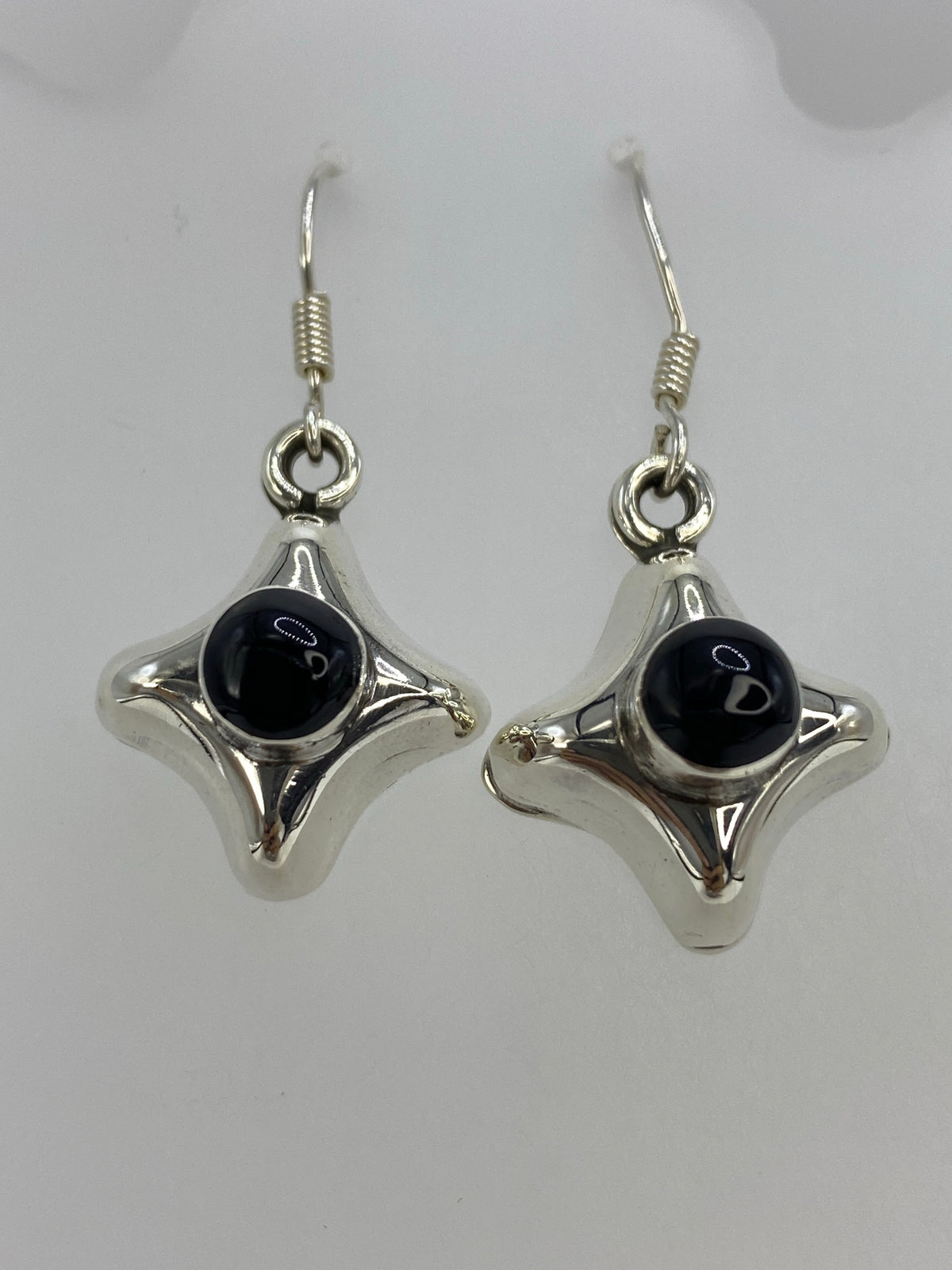 Detalle frontal de los aretes mostrando el ónix negro engastado y el diseño geométrico