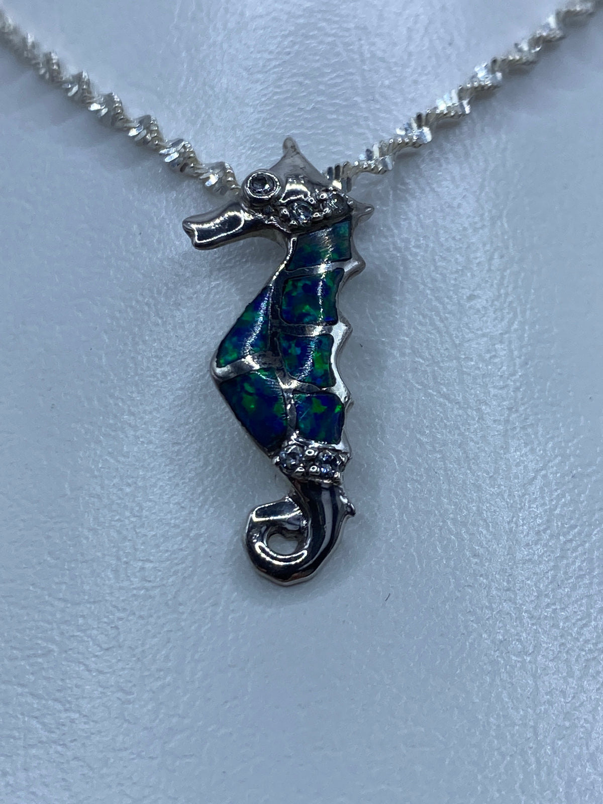 Dije de caballito de mar en plata 925 con ópalo azul y circonia blanca sobre cadena plateada