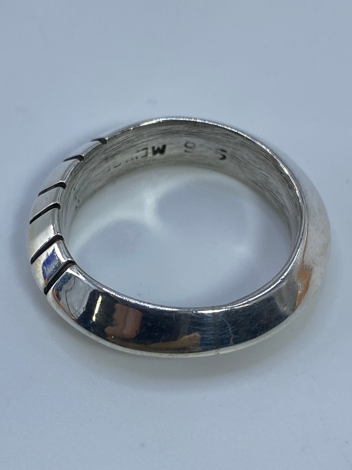 Anillo puesto en la mano mostrando cómo juega la luz en las facetas geométricas