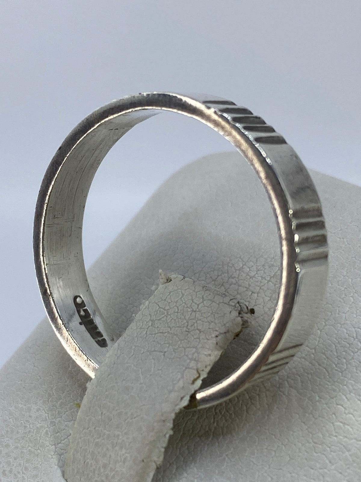 Anillo de plata geométrico puesto en el dedo anular, vista lateral