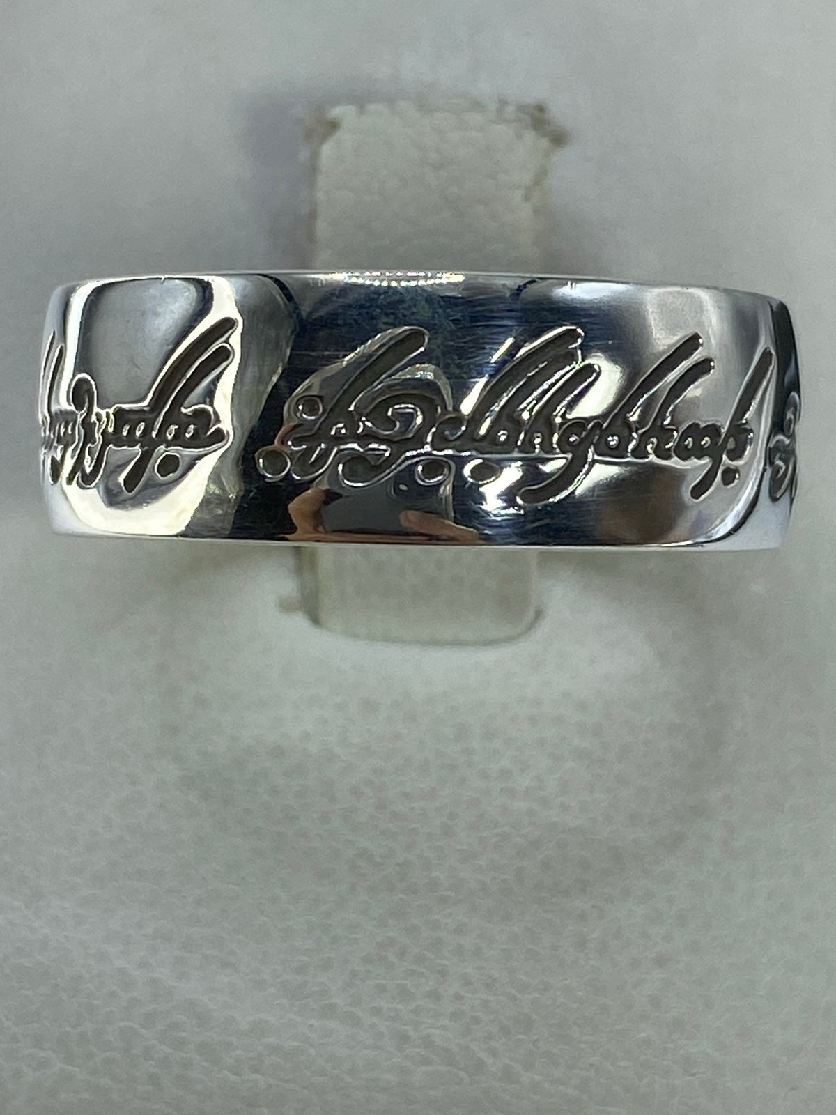 Anillo de plata banda ancha pulida en talla 13, visto desde arriba en fondo blanco