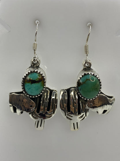 Par de aretes de plata con motivo de cactus y turquesa azul, colgando sobre fondo blanco