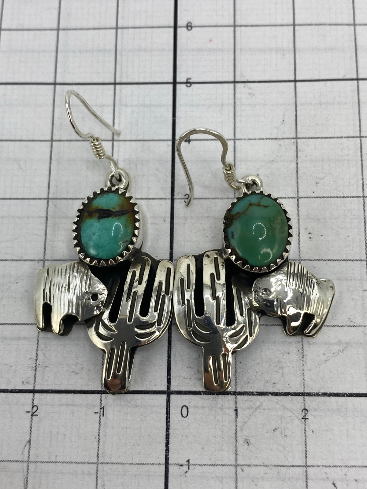 Aretes sobre regla de medición mostrando largo de 4.9 cm y ancho de 2.4 cm