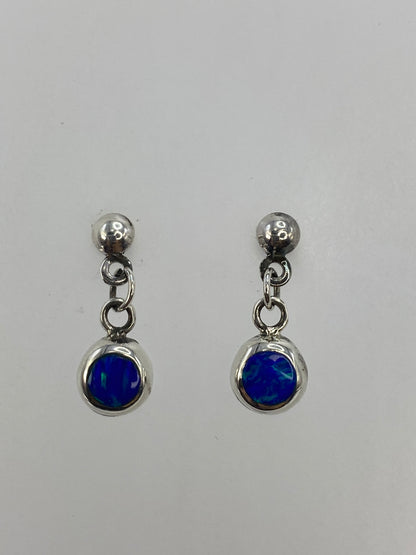 Par de aretes de plata con ópalo de fuego azul engastado, vistos de frente
