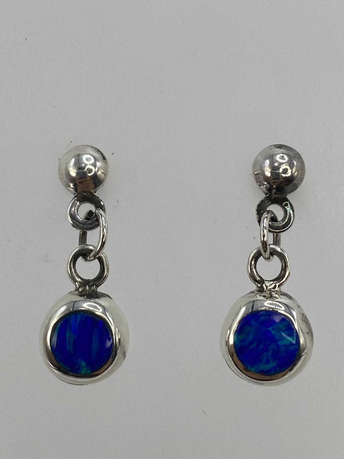 Aretes sobre paño blanco con medidor de escala, 2 cm de largo