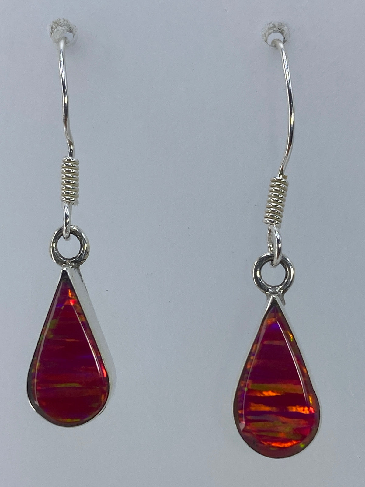 Aretes de plata con ópalo de fuego rosa en forma de gota, colgando en la oreja