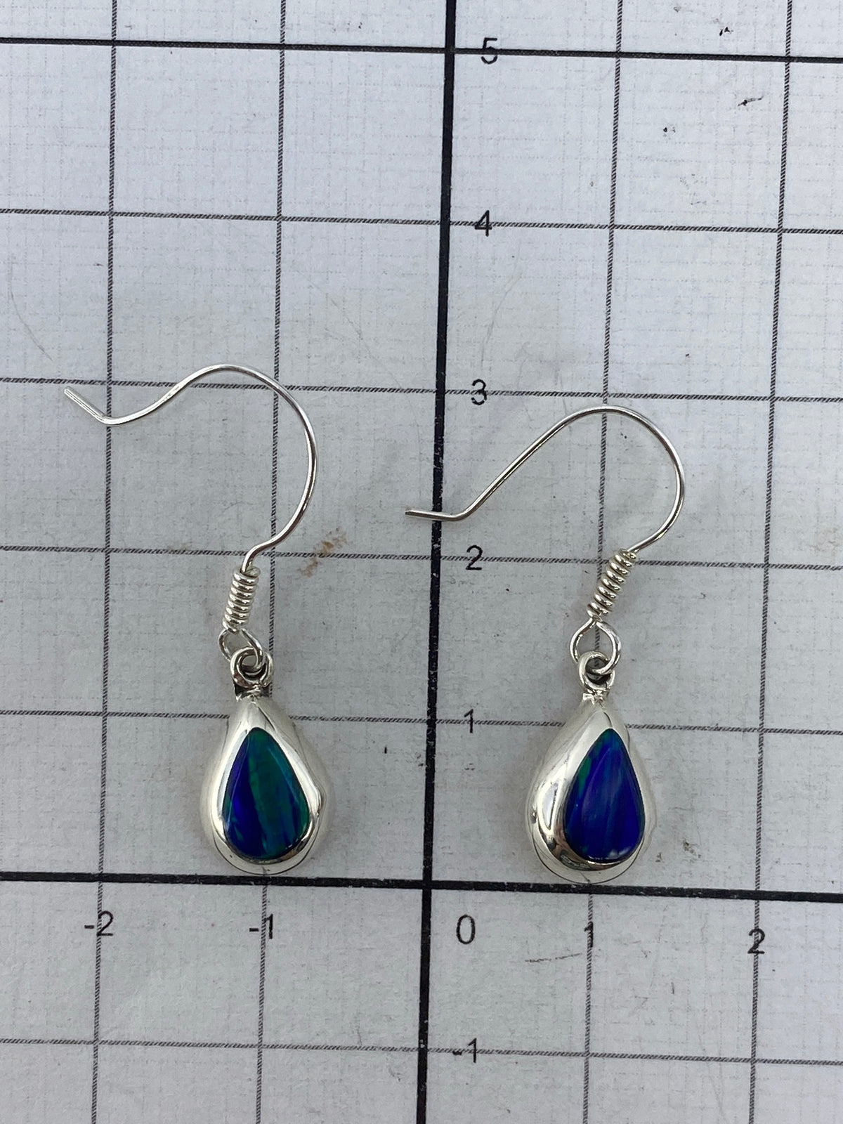 Aretes colgando, evidenciando el color verde y los destellos del ópalo de fuego