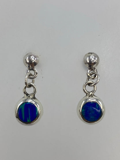 Par de aretes de plata 925 con ópalo de fuego azul, colgando sobre fondo blanco